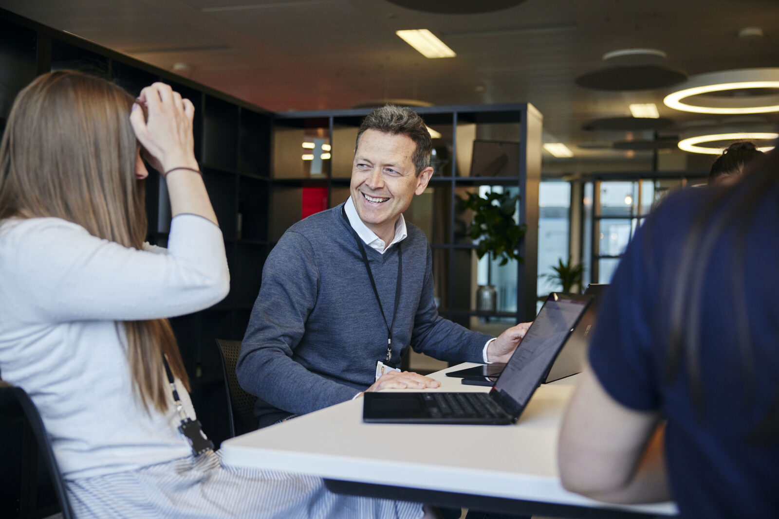 people smiling and in discussion around a laptop in an office