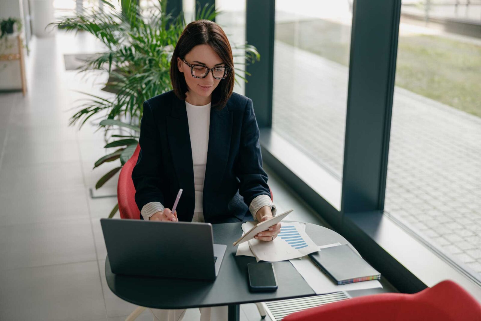 Professional woman working in lobby foyter with laptop, phone and papers